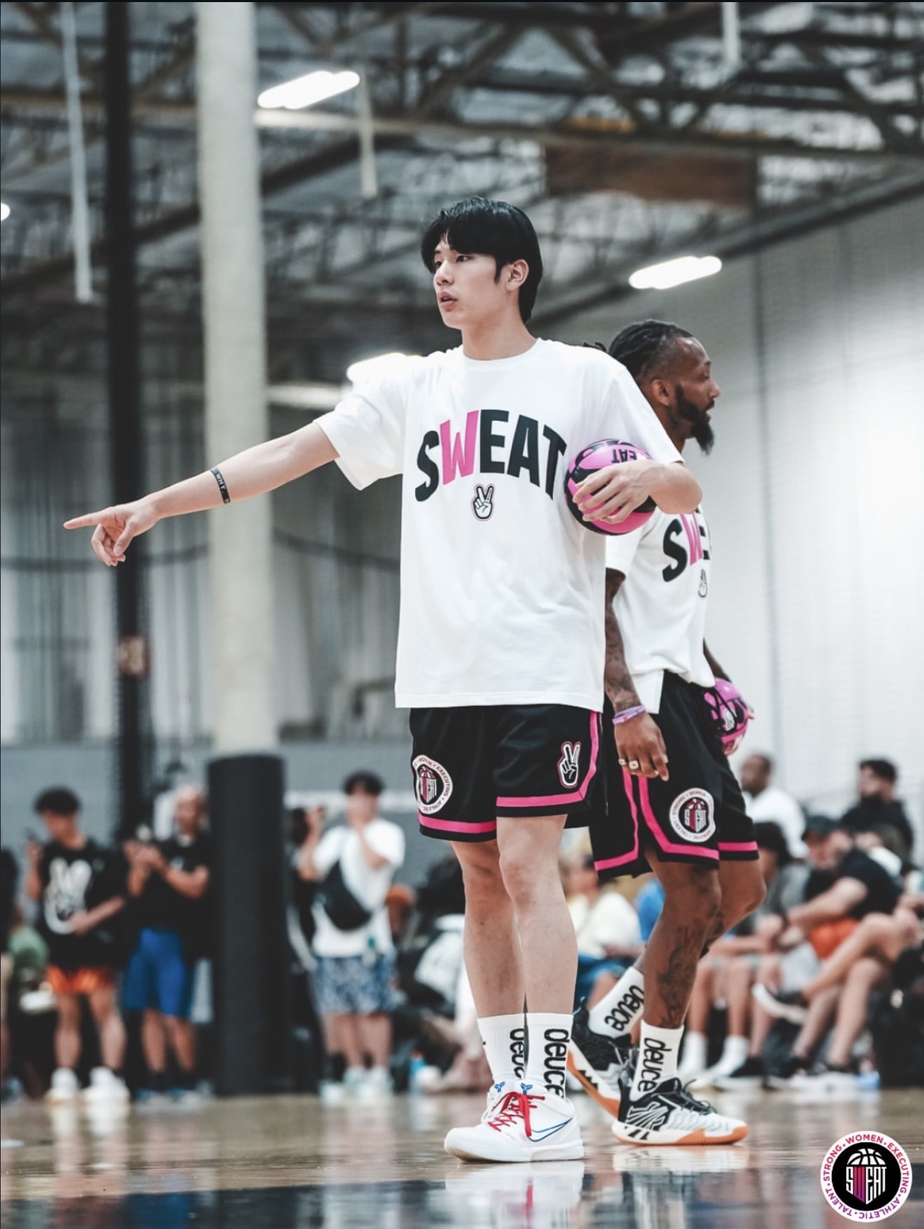 SWEAT CAMPのコートで、ボールを持ちながら指導するコーチ